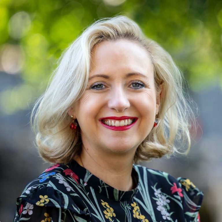 smiling woman wearing floral blouse with a blonde bob