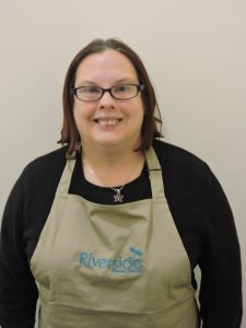 smiling woman wearing glasses and an apron