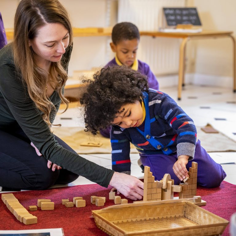 teacher helping child build a castle