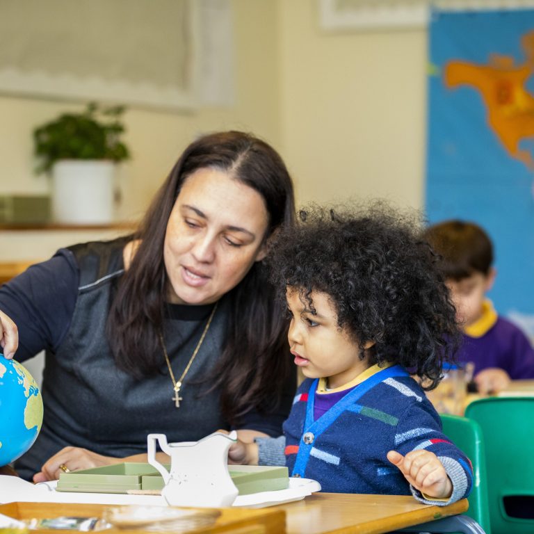 teacher pointing and showing a child a spot on the globe