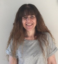 Smiling woman with long wavy brown hair and a fringe